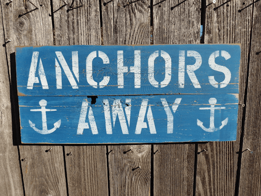 Rustic "Anchors Away" sign with anchor symbols, perfect for a nautical theme.