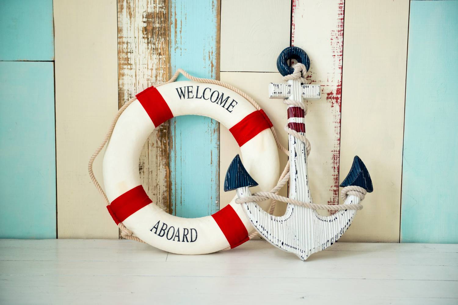 Lifebuoy and anchor against a rustic wood backdrop, with a nautical theme.