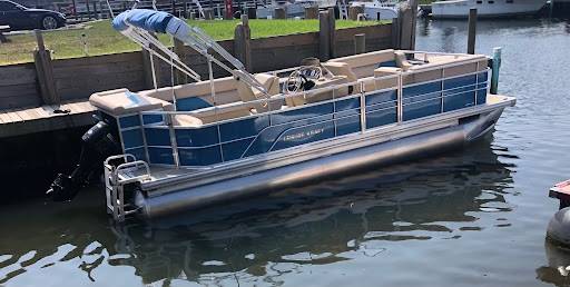A blue and white pontoon boat docked, from Ultimate Pontoon Guide.