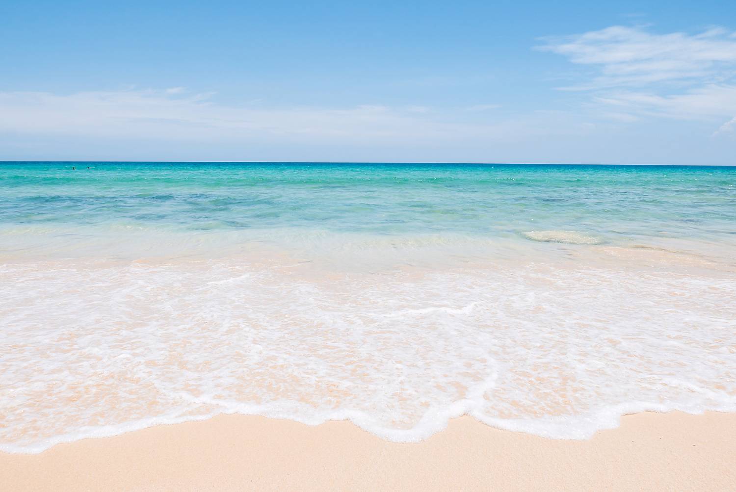 Pristine beach with crystal clear water under a clear blue sky, serene and inviting.