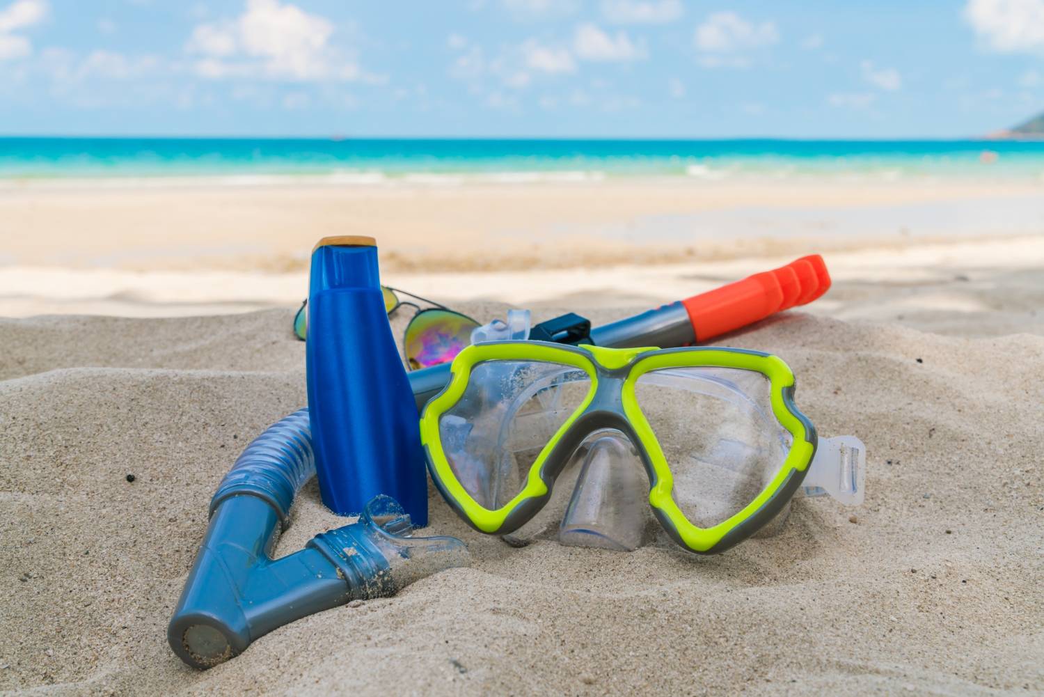 Snorkeling gear on the beach with clear blue waters in the background, ready for underwater exploration.