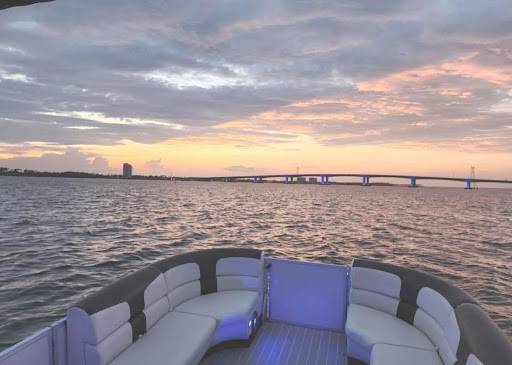 Sunset view from a pontoon in Panama City with purple accent lights and a bridge in the distance.