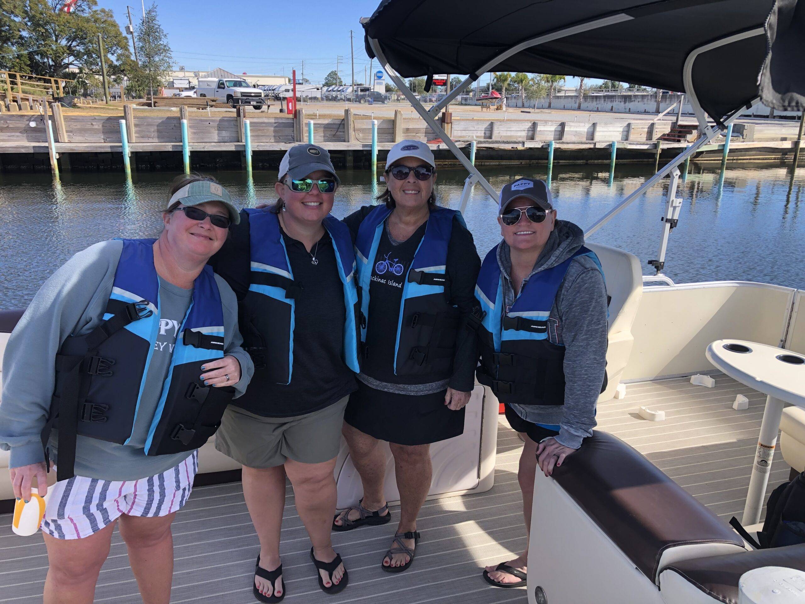 Four friends in life jackets, all set for a day on an 11-person pontoon boat.