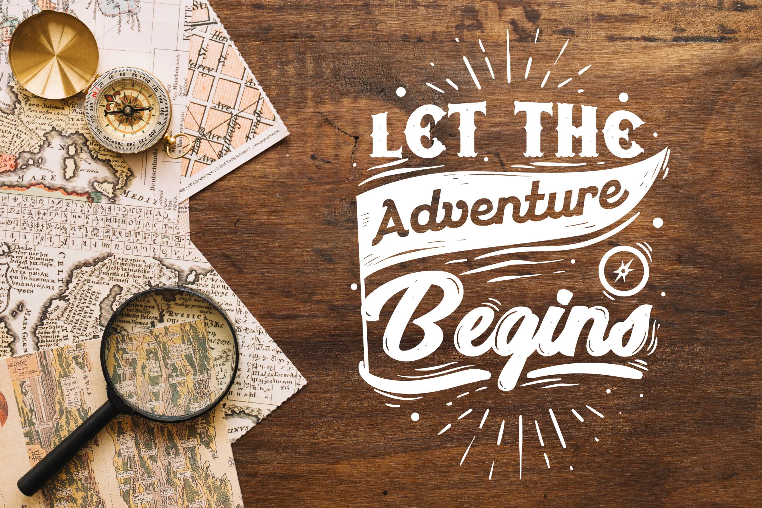 Vintage maps, compass, and magnifying glass on a desk with "Let The Adventure Begins" text.