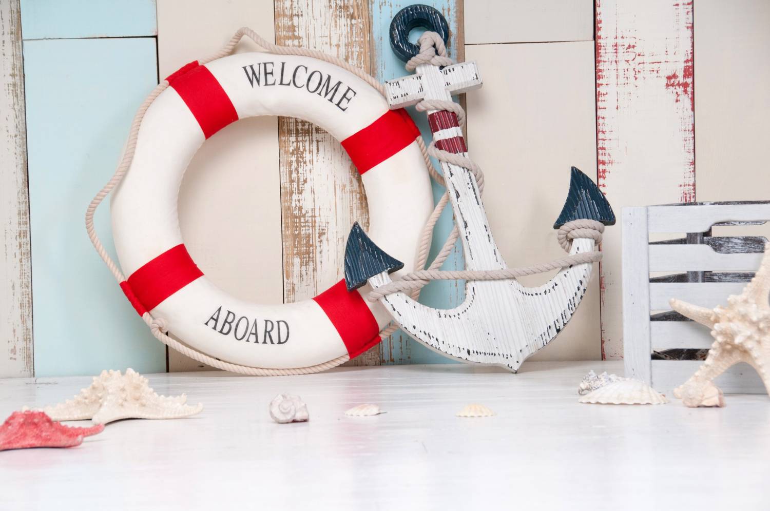 A lifebuoy and anchor decoration with the phrase "WELCOME ABOARD" against a rustic background, suggesting nautical home decor.