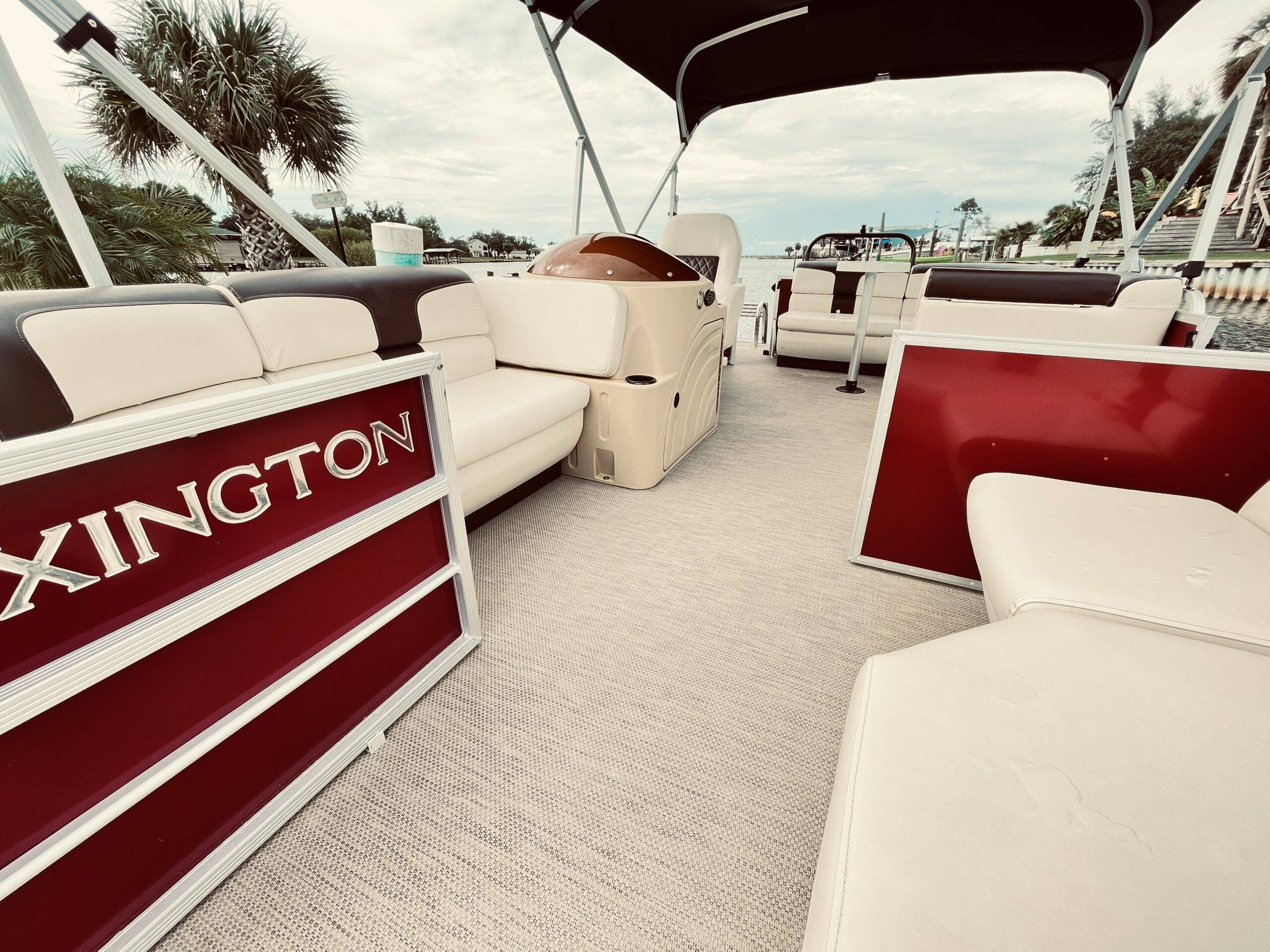 Alt text: "Hideaway Pontoon Rental's deck, red and cream seats, calm water, ready for a relaxing cruise."