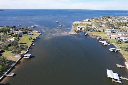 Aerial view of a calm bayou, ideal for pontoon rentals in Panama City, with docks and homes lining the shore.
