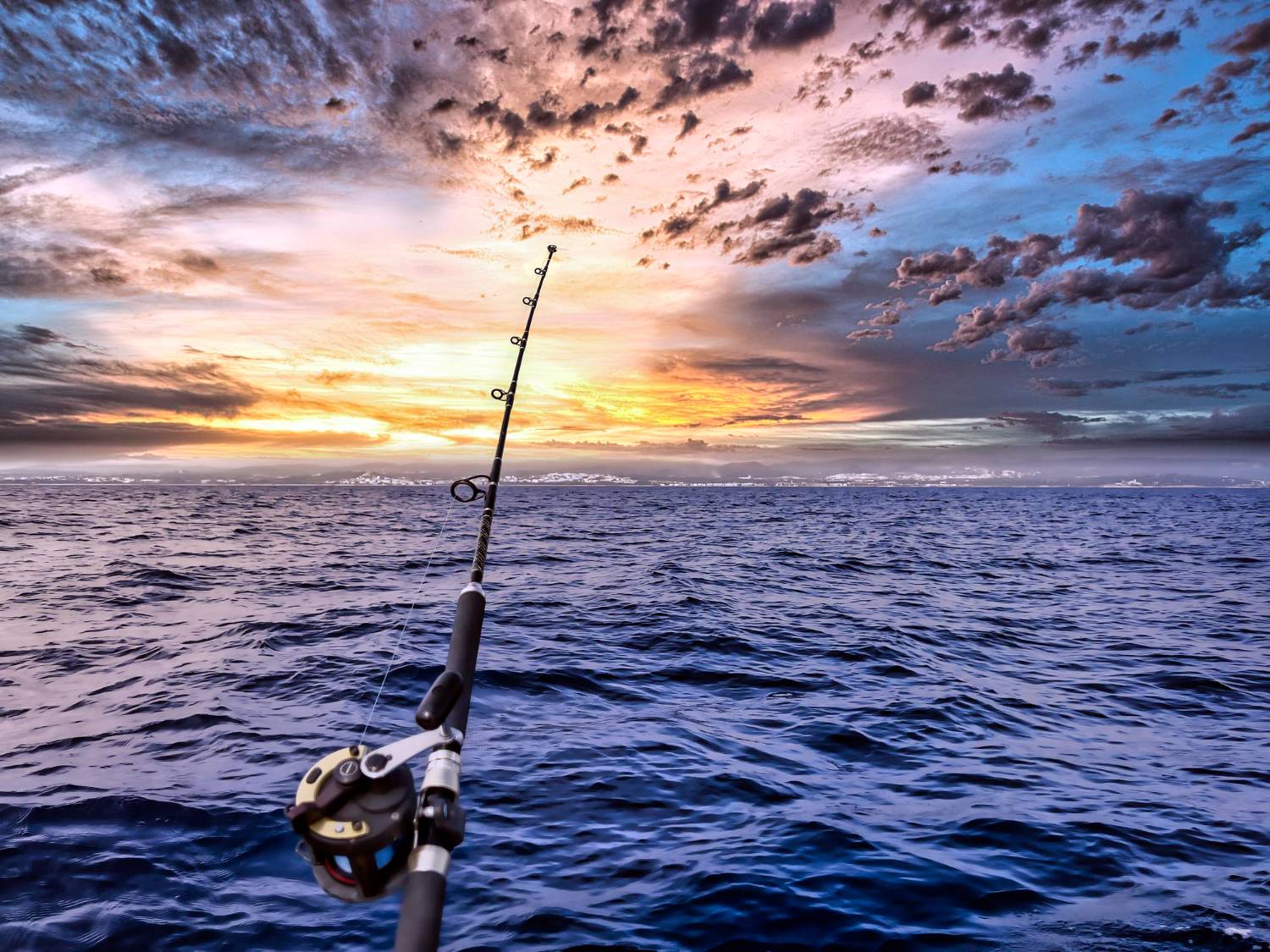 A fishing rod cast into the Gulf waters at sunset, symbolizing the ultimate fishing in the Gulf experience with breathtaking views.